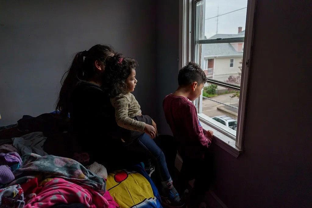 Image of a person and two children looking out of window