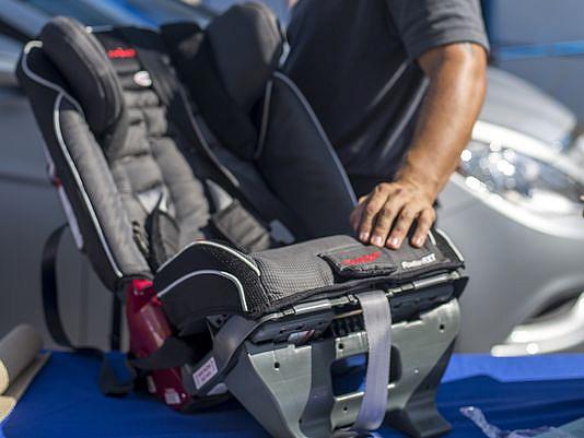 Augustine Lopez with the Tuscon Police Department with a child’s car seat at a Child Passenger Safety car seat check in June. (Photo: Rachael Le Goubin/The Republic)