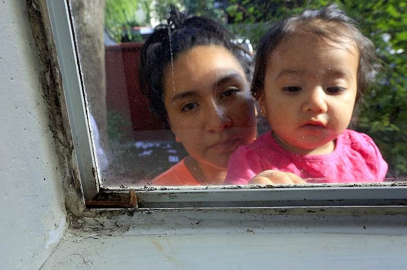 Guadalupe Vargas with her daughter Jaylani, 1, outside their mold covered bedroom window at the Walnut Creek Apartments on Jennings Ave. in Santa Rosa. (John Burgess/The Press Democrat)