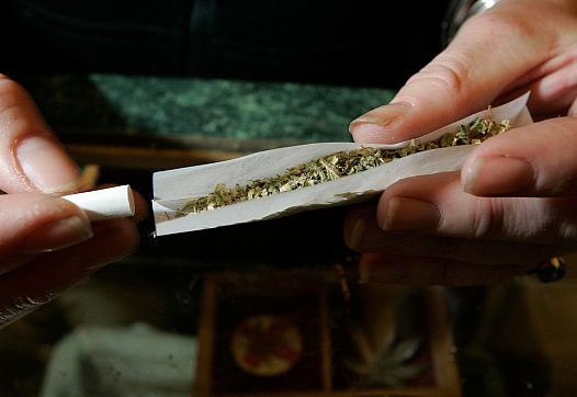 A worker at an alternative health services cannabis dispensary rolls a marijuana cigarette.