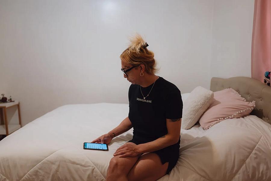 Image of a person sitting on bed using their phone