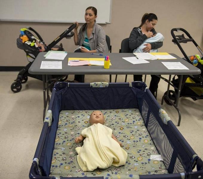 Mayra Perez, left, and her sister, Adriana, attend a safe-sleeping workshop in Meadowview. Public health officials recommend that parents lay babies down alone, on their backs, in cribs bare of anything except a tightly fitted sheet to reduce the risk of sudden unexpected infant death.