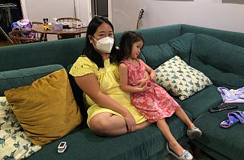 Anna Almendrala takes a short break from her oxygen concentrator to watch TV with her daughter, Marigold "Goldie" Ganz, three da