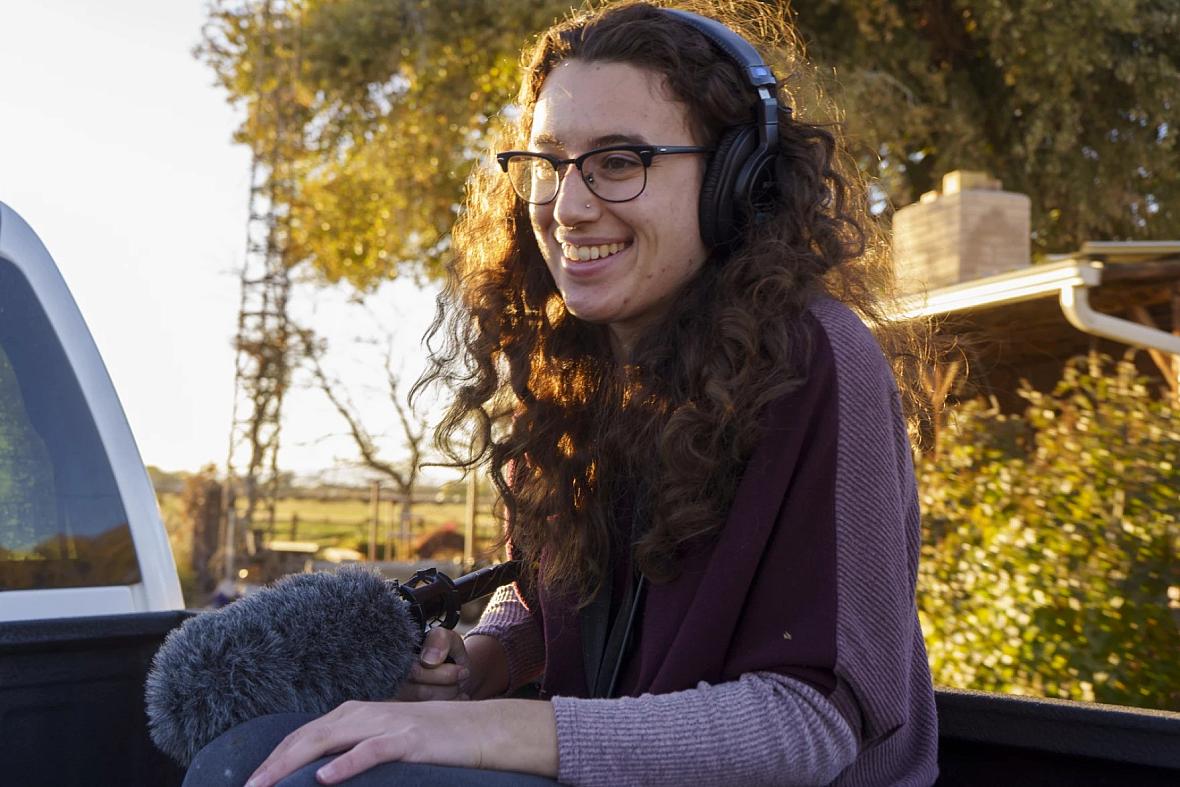 Image of a person holding mic and wearing headphones smiling
