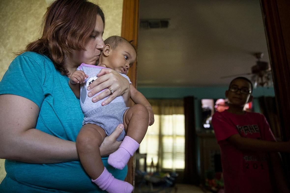 Angelica Castaneda, 30, kisses her daughter Jasmin while son, Andrew Castaneda, watches from the living room. Angelica Castaneda, 30, kisses her daughter Jasmin while son, Andrew Castaneda, watches from the living room.