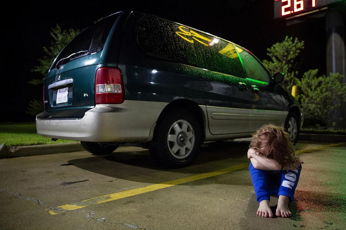 In a Victoria motel parking lot, Zoey Bowman sits on the ground and pouts in front of her mother's minivan in September.