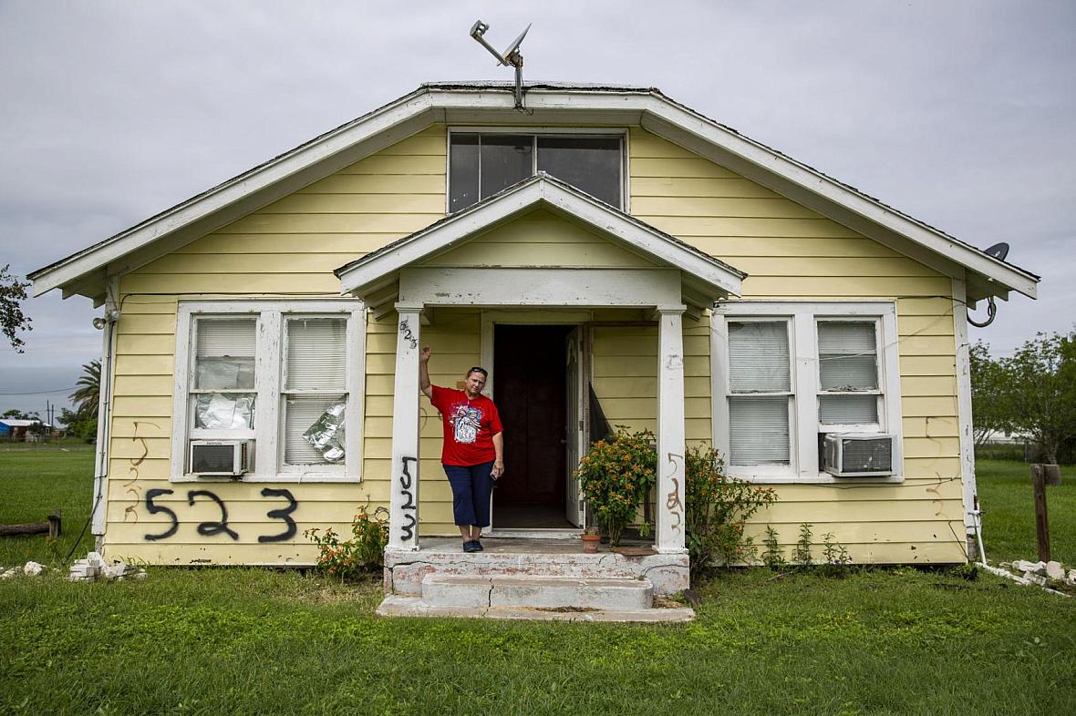 Sabine Wiegand, 55, leans against her abandoned home on 2nd Street in Bayside. Her mother, Patricia Wiegand; daughter; and grand