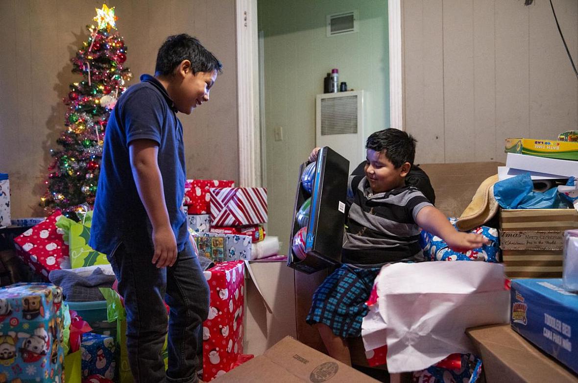Fernando Martinez, 10, left, watches his brother, Jonathan Sanchez Jr., 6, open shiny sport balls after gifts were brought to the family by good Samaritans. Fernando Martinez, 10, left, watches his brother, Jonathan Sanchez Jr., 6, open shiny sport balls after gifts were brought to th