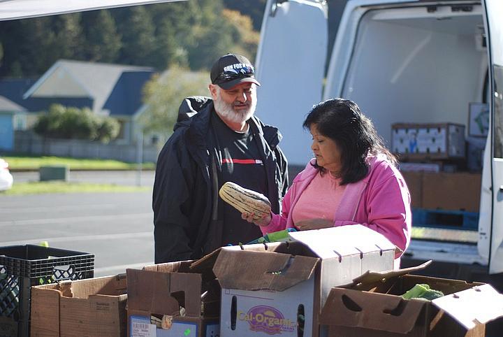 Shayne Britt and Roxie Reyes examine a delicata squash at an October visit of Food For People's Mobile Produce Pantry to Klamath