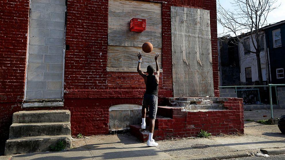 A boy shoots a basketball into a makeshift basket made from a milk crate and attached to a vacant row house in Baltimore, April 8, 2013. Patrick Semansky/AP Photo