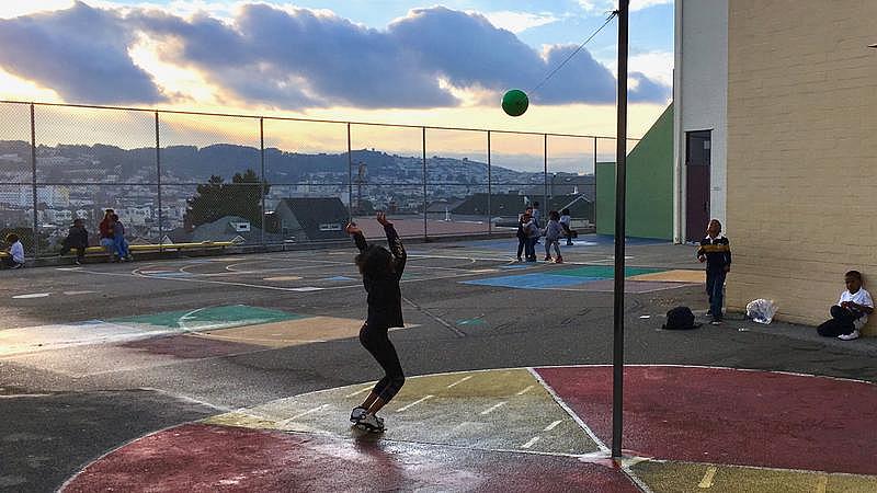 A Carver Elementary School student plays tetherball on the schoolyard at sunset with a staffer from the after-school program.