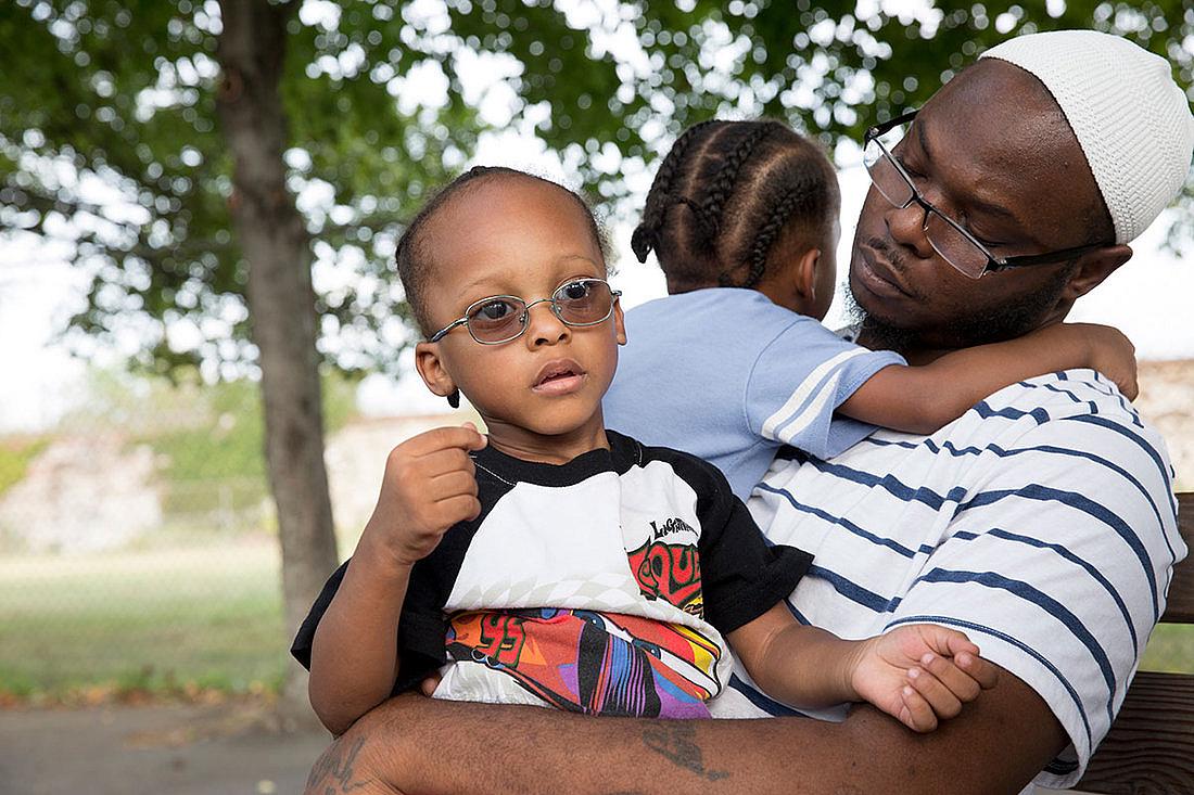 (Left to Right) Jihad and Murad sit with their dad, Andrew Irby, in the park. Irby worries about the future of his twin sons, who were both exposed to high levels of lead in their rented home. (Left to Right) Jihad and Murad sit with their dad, Andrew Irby, in the park. Irby worries about the future of his twin sons.