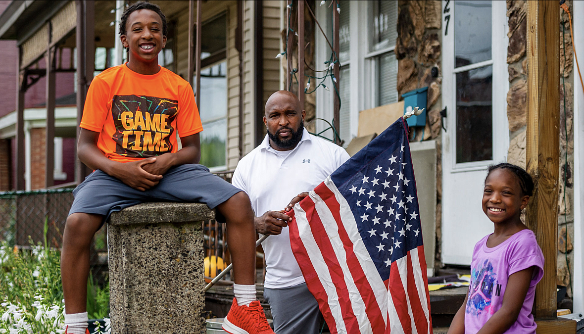 Jaden Weems, left, joins his father James Weems, who was in the process of installing a flag on his home, and Mr. Weems' daughte