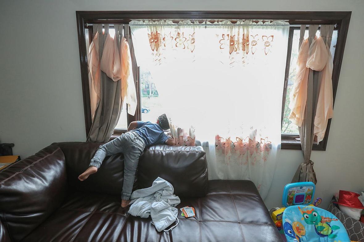 Jace Jarrett, 4, stands on his family’s large couch and peers out the window waiting for his father to come home from work on a 
