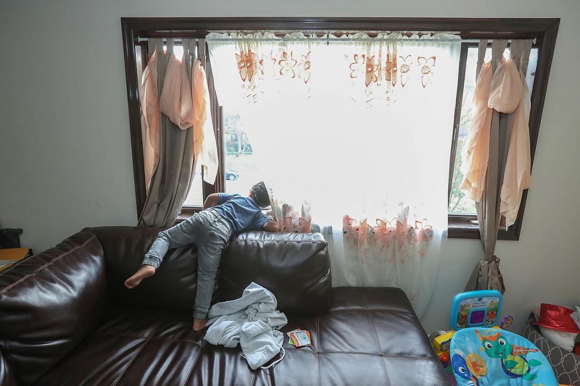 Jace Jarrett, 4, stands on his family’s large couch and peers out the window waiting for his father to come home from work on a