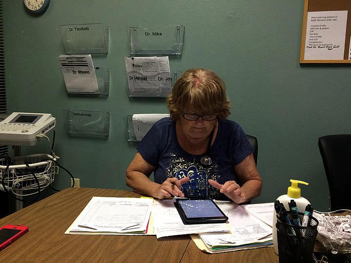 Donna Armes, director of The Haley Center in Winter Haven works on a patient's chart. Julio Ochoa / WUSF Public Media Donna Armes, director of The Haley Center in Winter Haven works on a patient's chart.