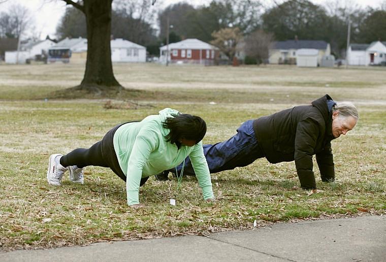 Marian DeVeaux, left, and Dick Seely challenged each other with 10 push ups near the end of their two-mile wellness walk around Fairfield Court and the surrounding neighborhood. They and others signed up for the walk through the Fairfield Court Resource Center. James Wallace