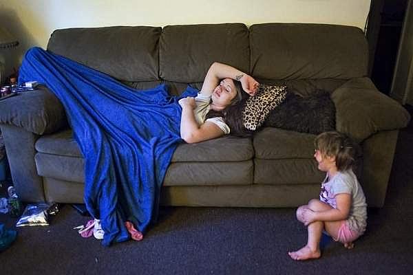 Brittany Crouch suffers through withdrawal symptoms, the day before leaving for treatment in Lexington, as her youngest daughter Kaylee Adams, 3, cries at the foot of the couch inside Crouch's brother's apartment living room in Frenchburg, Ky.