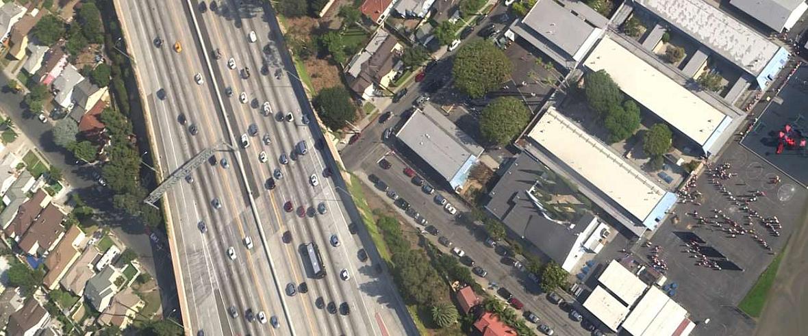 Students line up outside El Marino Language School as vehicles zoom by on Interstate 405 in Culver City, California.