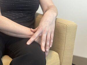 Image of hand of a person sitting on the couch.