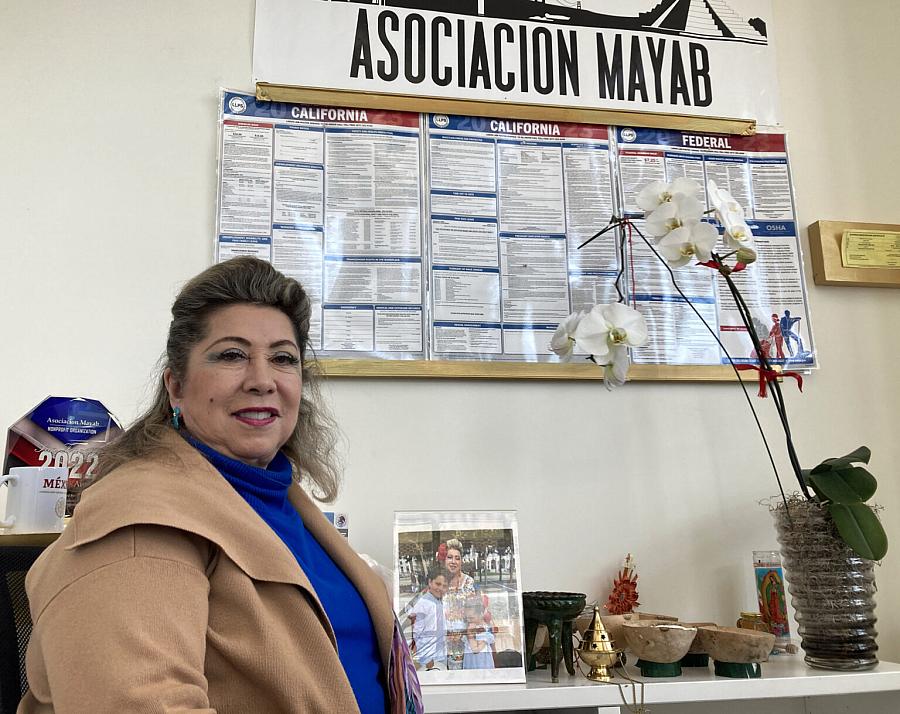Person looking at the camera sitting in front of a wall with "Asociacion Mayab" banner