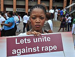 Black woman with sign that reads, "Let's unite against rape."