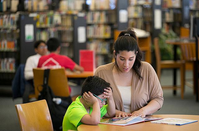 Cristine Pagan helps her son Dean with reading homework at a local library. When Dean started first grade at Comly Elementary last September, his classroom was filled with potentially hazardous deteriorating paint, and the school district knew it. (Photo Credit: Jessica Griffin/Philadelphia Inquirer) Cristine Pagan helps her son Dean with reading homework at a local library. When Dean started first grade at Comly Elementary la