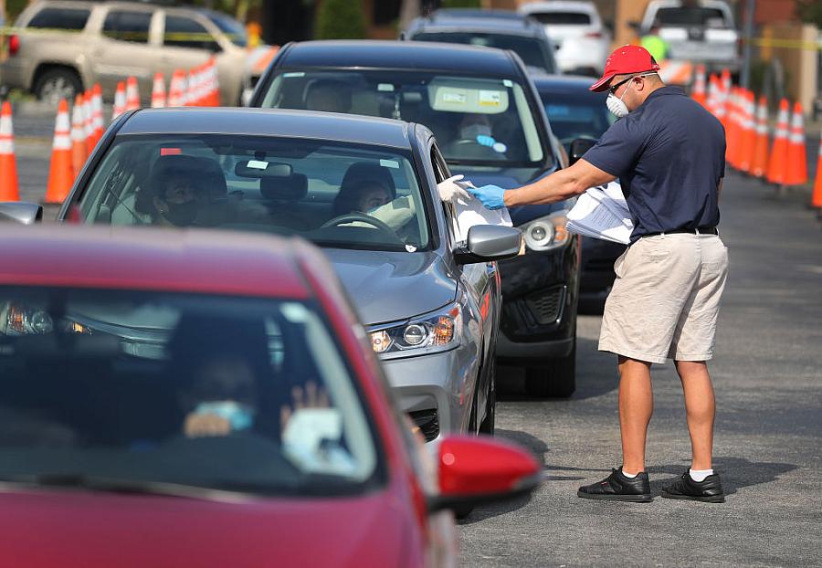 Miguel Diaz hands out unemployment applications to people in their vehicles in Hialeah, Florida, in the midst of widespread layo