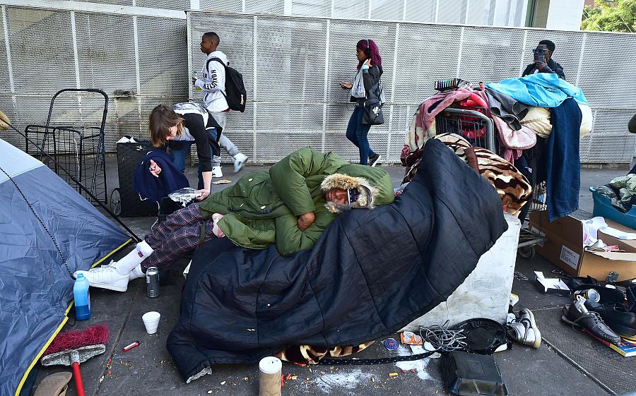 Homeless woman Caroline Francis places a platter of food for her neighbor on the street in downtown Los Angeles shortly before C