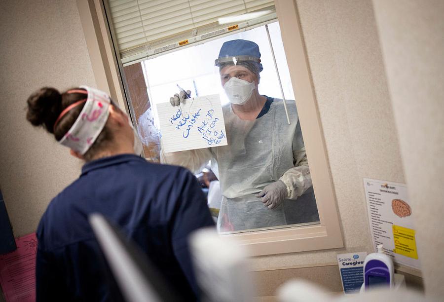 Nurses in the intensive care unit of MedStar St. Mary's Hospital communicate through a window with an erasable whiteboard from a