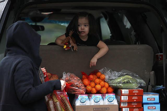A young girl looks on as a volunteer loads food into a car at a food bank in Santa Rosa, California. (Photo: Justin Sullivan/Getty Images) Photo: Justin Sullivan/Getty Images