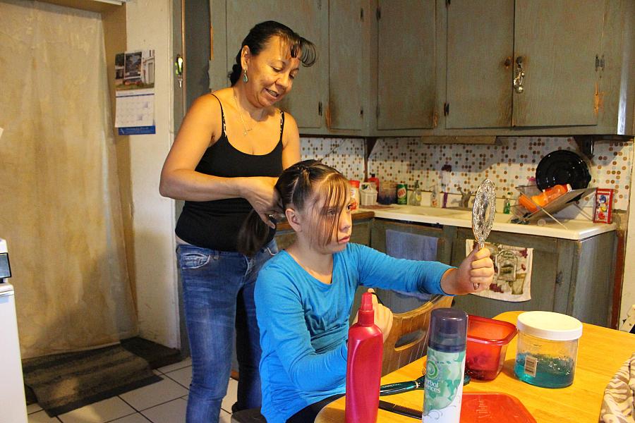 Lupe Salazar brushes her granddaughter Neveah's hair before school. Lupe's son has been in and out of jail his whole life for crimes related to his heroin addiction, and she is raising his two children. Photo