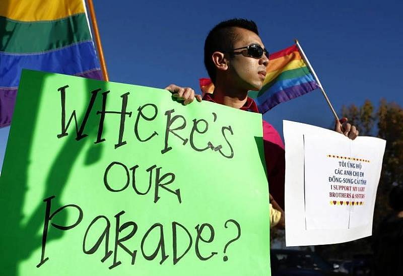 Minh Tran of Westminster holds a sign and Pride flag as he protests the exclusion of LGBT groups from the Tet parade in Little Saigon in 2013. (Allen J. Schaben / Los Angeles Times)