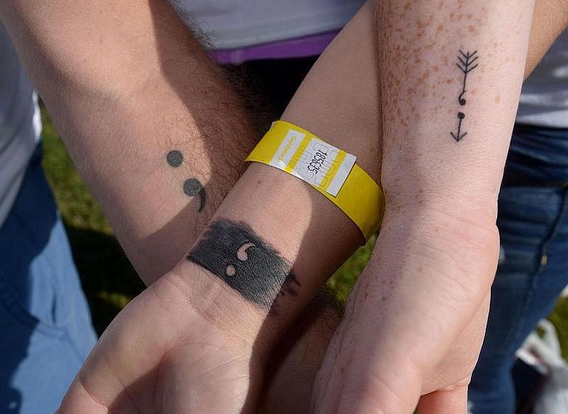 Dustin Moore (from left), Paige Thielbar and Tina Polk of Bentonville display their Team Semicolon tattoos in September 2016 during an annual walk to memorialize those lost to suicide and to raise awareness of suicide prevention. The team name and tattoos are inspired by Project Semicolon, a nonprofit campaign to bring hope to people dealing with depression, self-harm and thoughts of suicide. (NWA Democrat-Gazette/Ben Goff)