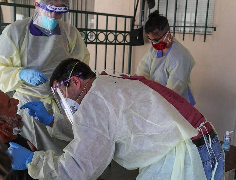Dr. Richard Loftus, bottom, administers a coronavirus test to an individual Our Lady of Guadalupe Church in Palm Springs, May 15, 2020. The Coachella Valley Volunteers in Medicine tested homeless individuals. Jay Calderon/ The Desert Sun
