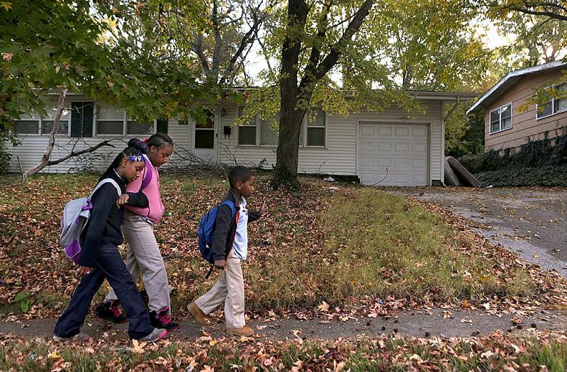 “It’s a best friend thing. We always be holding on to each other,” says Destiny Sonnier (center), 9, who walks with her friend, Akeelah Kelly, 8, to the school bus stop in Ferguson in October with Destiny’s cousin Anthony Murry, 6. Their friend Jamyla Bolden was killed in her home across the street.