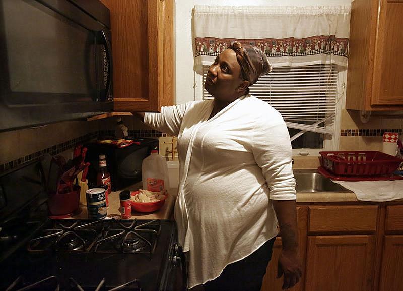 Natasha Brown, 30, cooks dinner in October at her home in Ferguson. Brown, who lived most of her life in St. Louis, can’t wait for her Section 8 subsidized housing lease to run out so she can move her girls out of Ferguson.