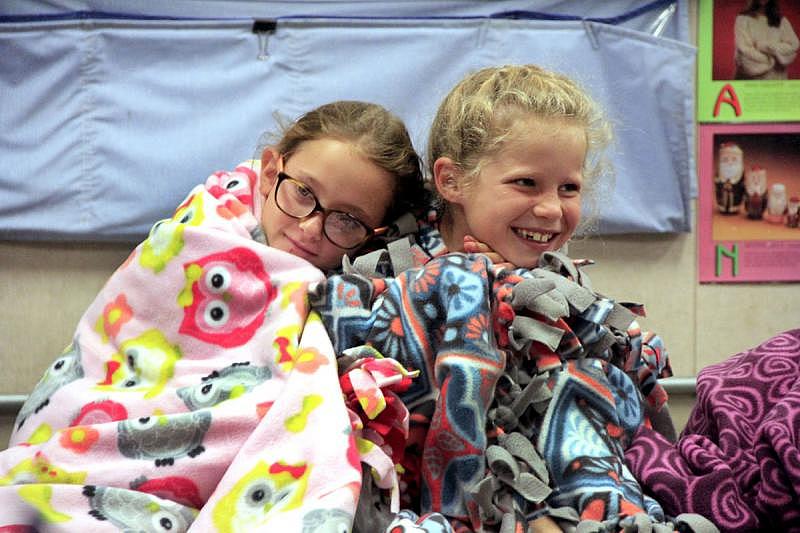 Samantha Wyly and Charlotte Hafenfeld snuggle up in handmade quilts donated to those who attended Camp Noah, which helps kids who have suffered trauma from natural disasters, like the Erskine fire, cope and recover. 