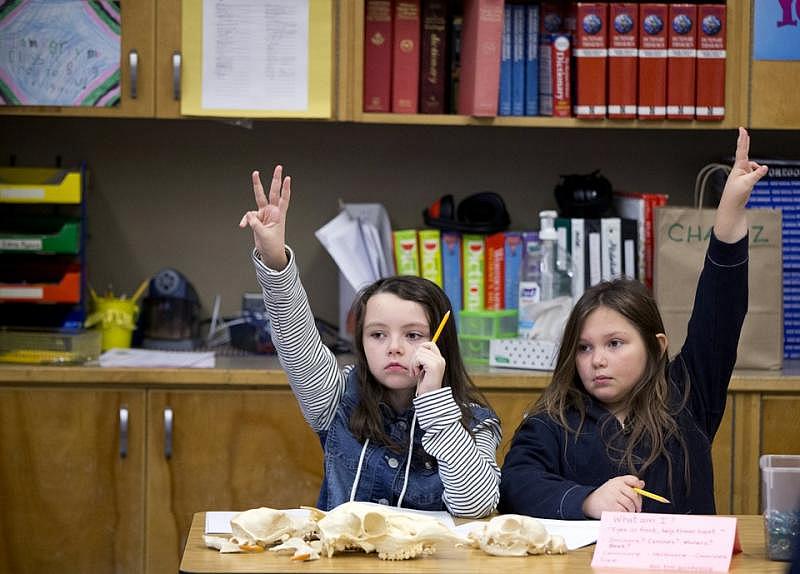 Kaitlin Moran, left, and Gladys Criswell raise their hands in Ordella Reynolds' fourth-grade class.