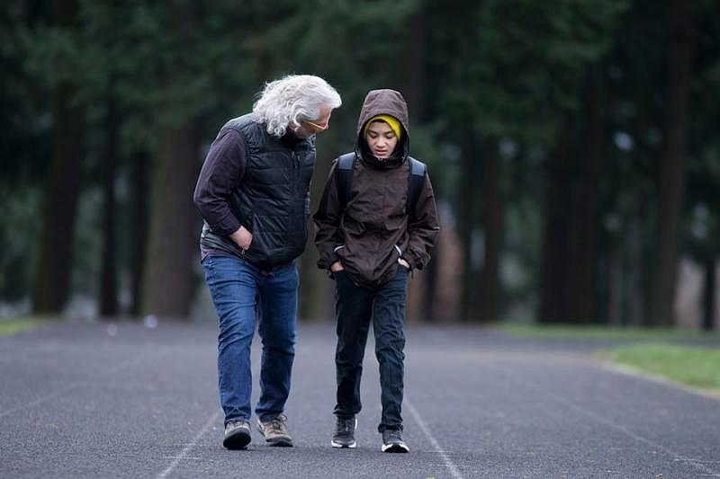 David Poulshock walks around the track with his grandson, James, before James catches the morning school bus. Due to his daughter Nina's work schedule, David sometimes pitches in supervising his three grandchildren as they prepare for school. 