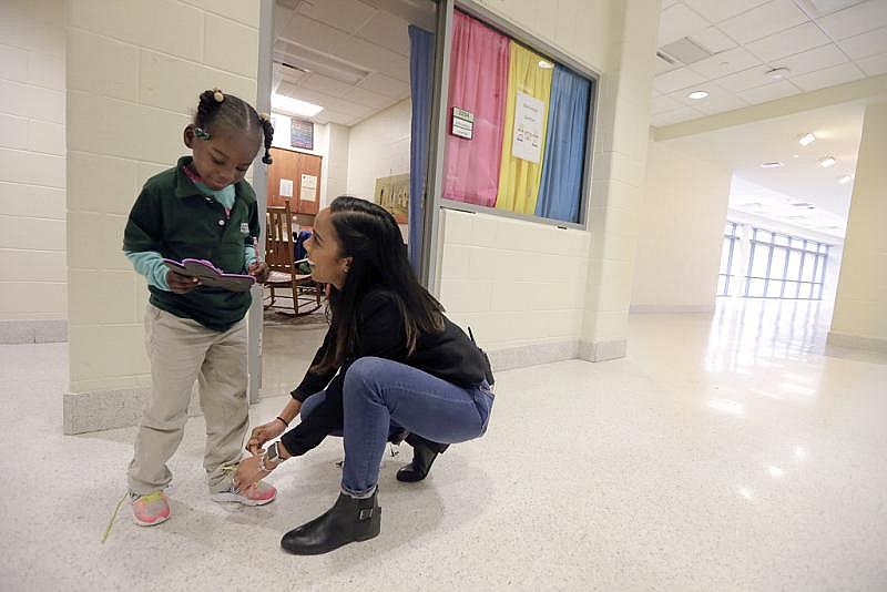 Crocker College Prep principal Nicole Boykins ties a student's shoe for her at the school in New Orleans.