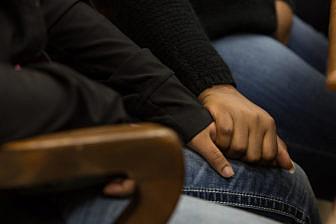 Ashley Patrick clasps the hand of her daughter, Dationna Price, during a Restorative Justice Louisville meeting in January 2018.