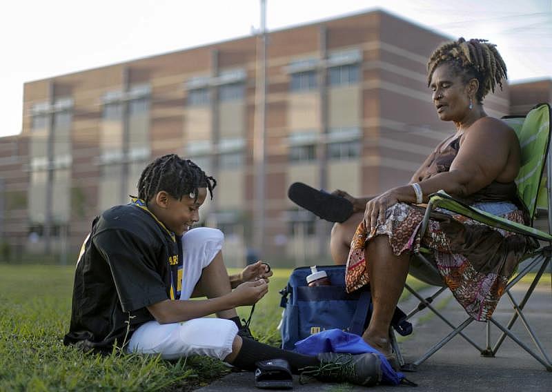 Ji'Air Luckie, 10, chats with his grandmother, Paulette Young, as he laces up his shoes for football practice at A.L. Davis Park in Central City.