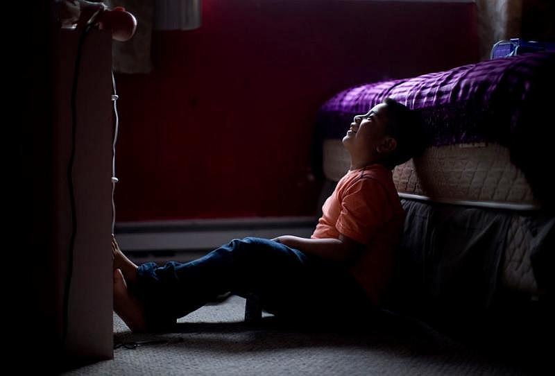 Eric Ku-Castillo, 7, a student at Rigler Elementary School, watches cartoons after school inside his family's home at The Normandy Apartments in January 2017. His family, along with several others, received a 100 percent rent increase. 