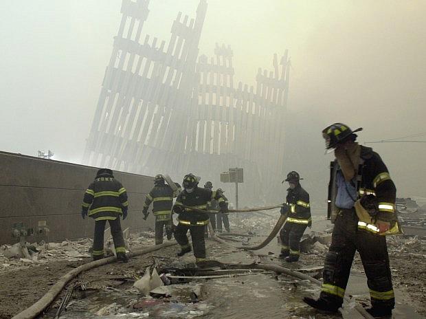 FILE – In this Sept. 11, 2001 file photo, firefighters work beneath the destroyed mullions, the vertical struts which once faced the soaring outer walls of the World Trade Center towers, after a terrorist attack on the twin towers in New York. (AP Photo/Mark Lennihan)