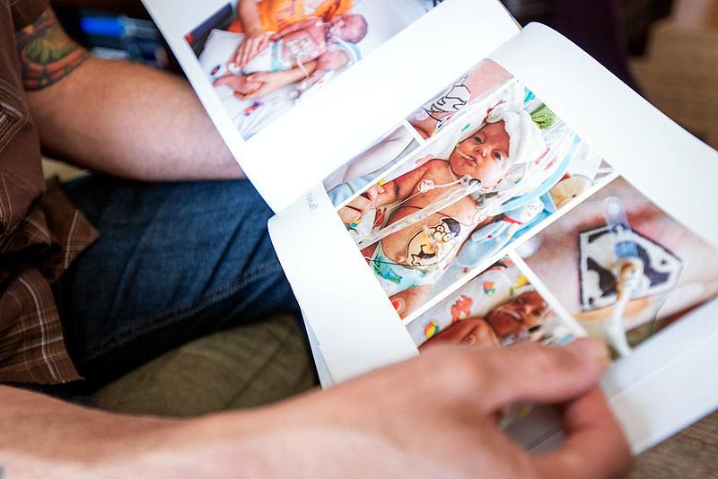 Omar looks through Kai's photo book. The charges for the infant's six months of care in the neonatal intensive care unit totaled about $11 million, according to the family, though their insurer very likely negotiated a lower rate. Heidi de Marco/KHN