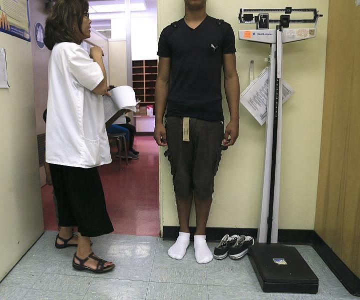 Nurse Practitioner Joyce Yoshimizu weighs and measures a student enrolling in the LAUSD. || Photo Credit: Mark Boster/Los Angeles Times/Getty Images