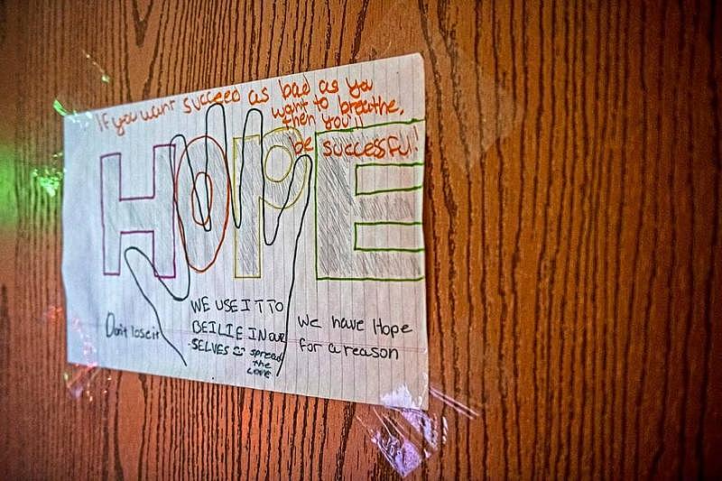 A drawing with the word “Hope” along with inspirational words hangs on the door to Jared Todd's room as he plays the video game “Warframe” at his home in Hawkins Village.