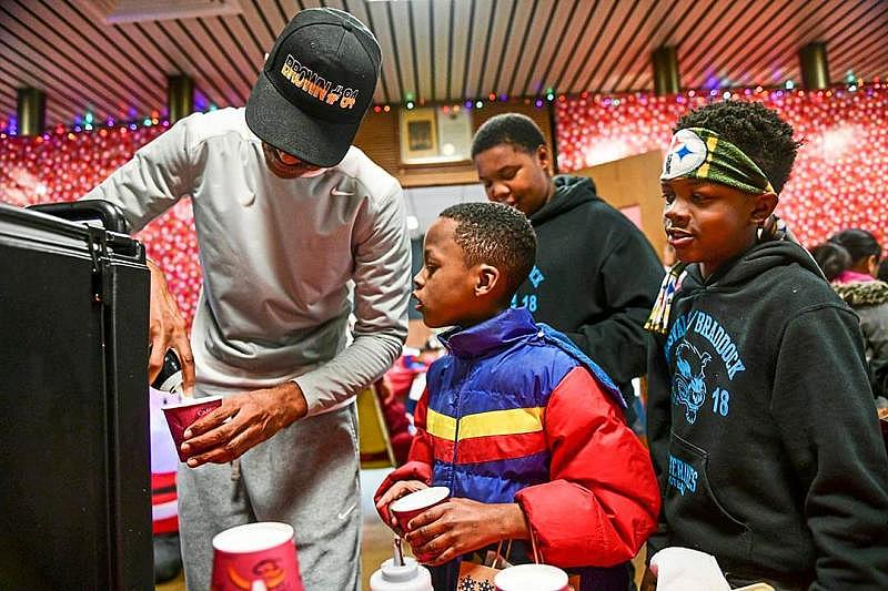 Demont Coleman, former mayor of Rankin, left, puts whipped cream on a hot chocolate as Eric Ramsey, center, and Tyshawn Champine, right, both of Rankin, look on during the Rankin Borough Holiday Night, Dec. 12, in the borough building.
