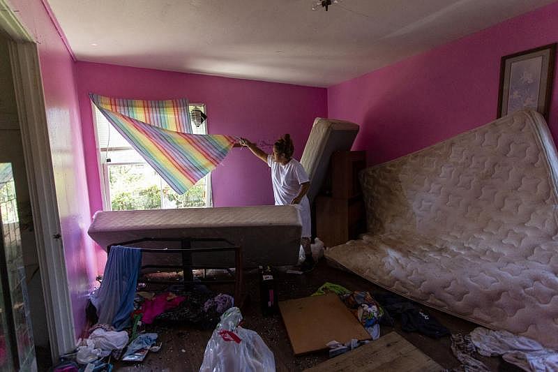 Barrientes lifts a curtain to show a broken window. The mother said she attempted to barricade the window with a mattress during Hurricane Harvey, but the winds were too strong. Broken glass, clothing and a water-damaged mattress are scattered across the bedroom floor. (Photo Credit: Angela Piazza/Victoria Advocate) Barrientes lifts a curtain to show a broken window. The mother said she attempted to barricade the window with a mattress during Hurricane Harvey, but the winds were too strong. Broken glass, clothing and a water-damaged mattress are scattered across the bedroom floor.